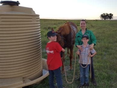 A woman and two boys standing next to a horse.