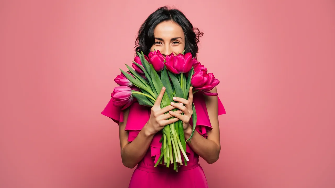 Woman in pink dress holding tulips.