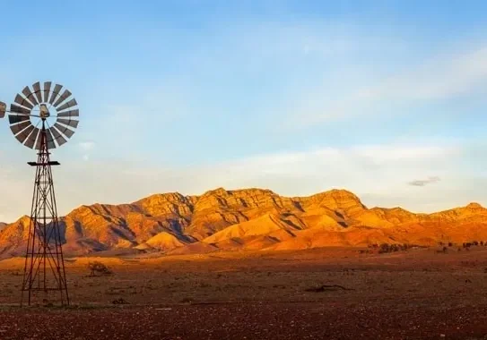 Windmill in desert with mountains.