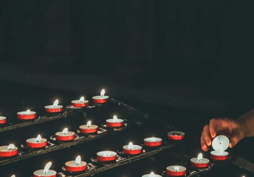 A person lighting candles on top of a table.
