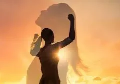 Woman silhouette with raised fist against sunset.